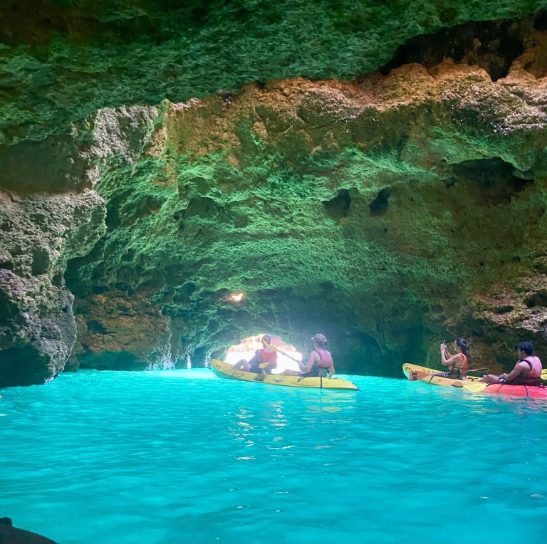 Kayakers in a cave with vibrant turquoise water